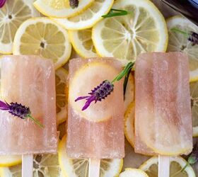 lavender gin lemonade popsicles, Three Lavender Gin Lemonade Popsicles in a row topped with fresh lavender flowers and laying alongside a bottle of Empress 1908 Gin