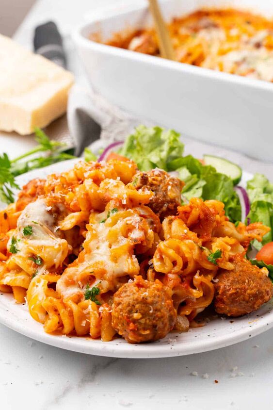 meatball casserole, Meatball casserole dished on a plate paired with a salad Baking dish is displayed in the background