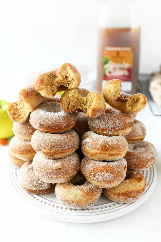 baked apple cider donuts, Apple cider sugared doughnuts on a white plate with an apple cider bottle behind them