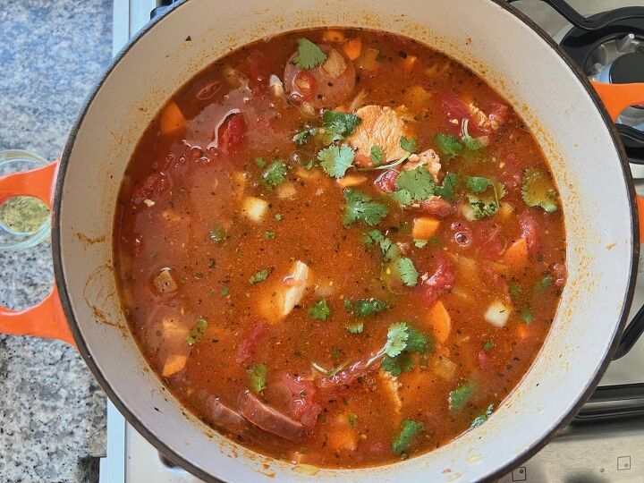 galinhada dutch oven chicken and rice, Fresh cilantro leaves added to tomatoes broth and chicken in pot for Galinhada Dutch Oven Chicken and Rice