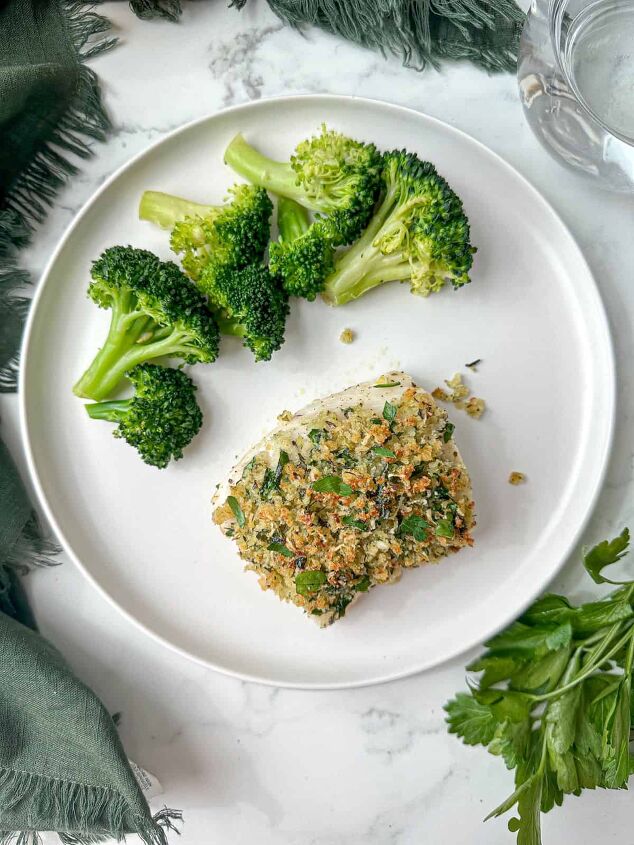 baked panko crusted cod, Baked parmesan crusted cod on a white plate with broccoli Crust is golden brown and sprinkled with green parsley