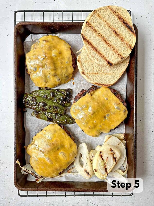 southwest burger with chipotle mayo, Three grilled burger patties with cheese on a sheet pan lined with parchment paper Grilled onions jalapeno and toasted buns surround the patties