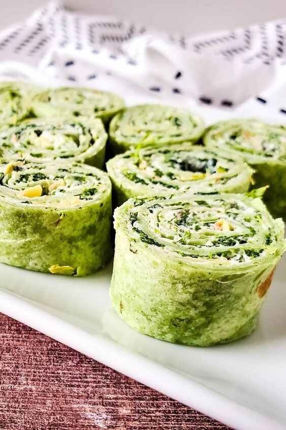 rolled spinach and artichoke pinwheel appetizers on white tray