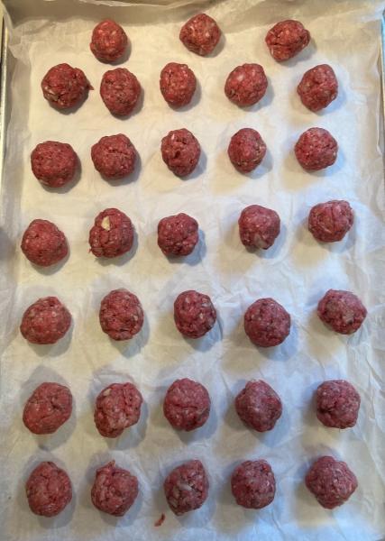 easy and delicious meatballs, raw meatballs on a cookie sheet with parchment paper