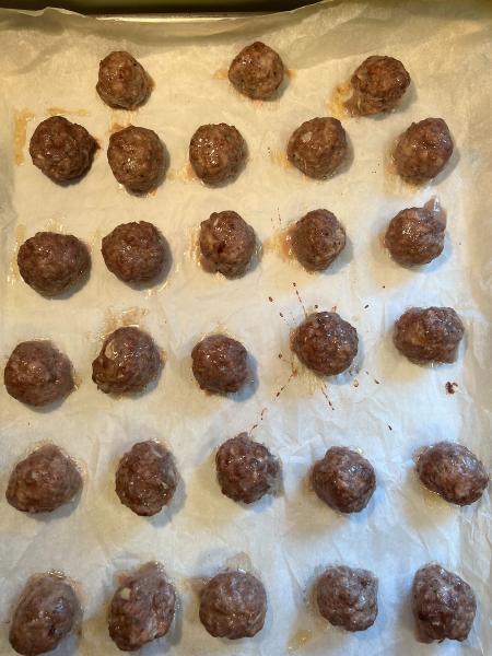 easy and delicious meatballs, baked meatballs on a cookie sheet with parchment paper
