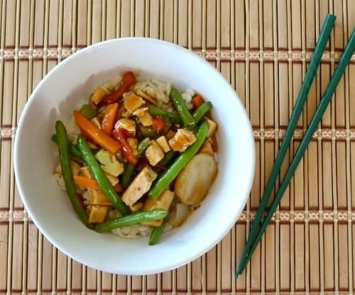 vegetarian rice pilaf, Tofu teriyaki in a white bowl with green chopsticks