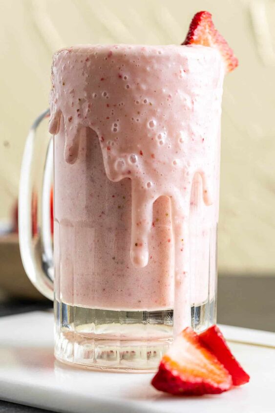 strawberry banana milkshake, close shot of strawberry banana milkshake with strawberries around the serving glass