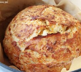 no knead cheddar bread in the dutch oven, Golden brown rustic cheddar bread in a dutch oven lined with parchment paper