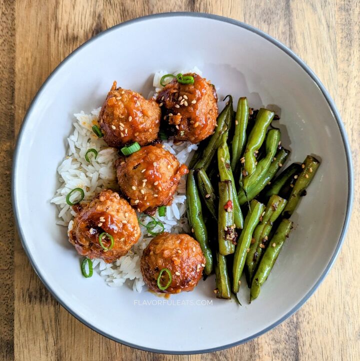 slow cooker spicy korean meatballs, White plate with rice topped with Slow Cooker Spicy Korean Meatballs with green beans on the side