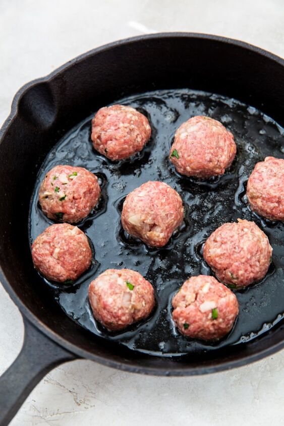 easy keto cast iron meatballs, raw keto meatballs being cooked in a cast iron skillet