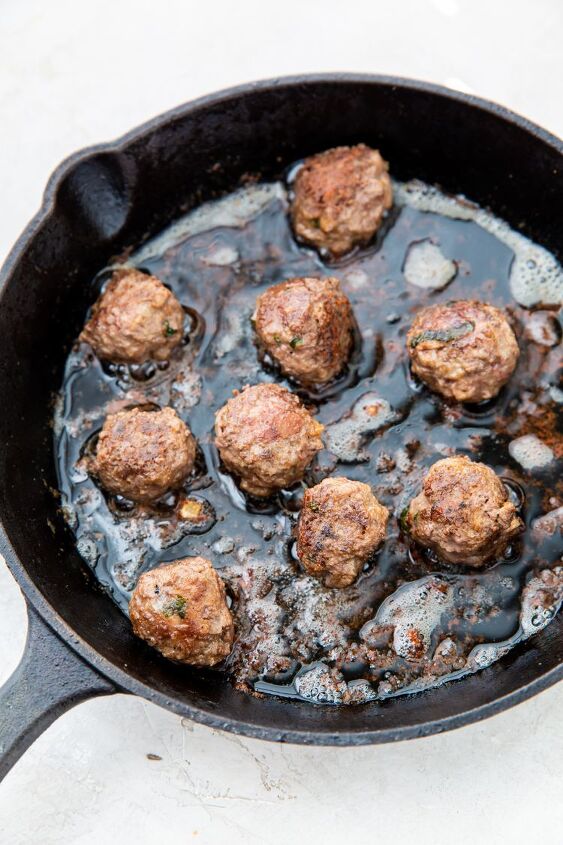 easy keto cast iron meatballs, keto meatballs being cooked in a cast iron skillet