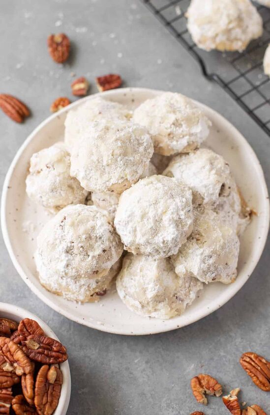 snowball cookie recipe with pecans, pecan snowball cookies piled on a plate with pecans laid around