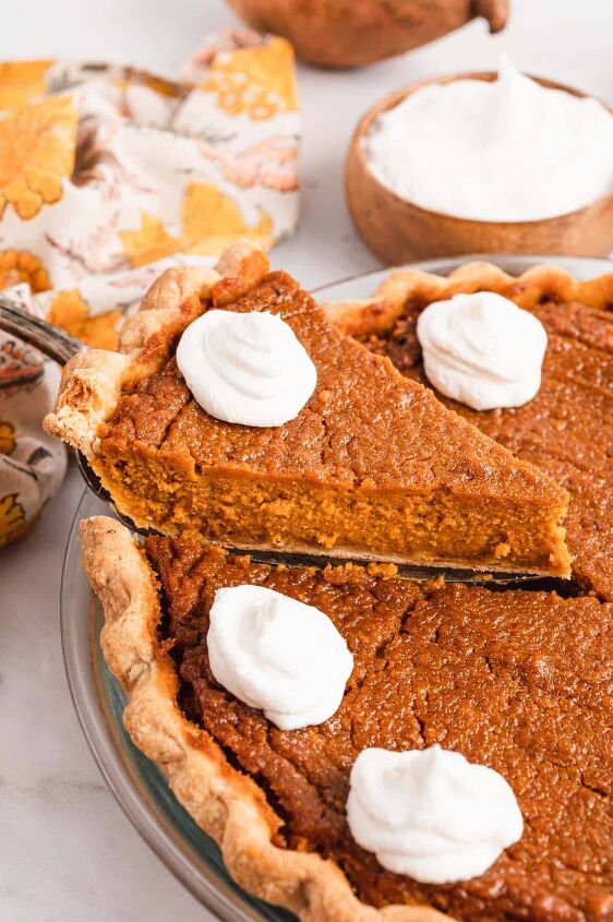 southern sweet potato pie recipe, A piece of sweet potato pie topped with a dollop of whipped cream being lifted away from the full pie by a serving spatula