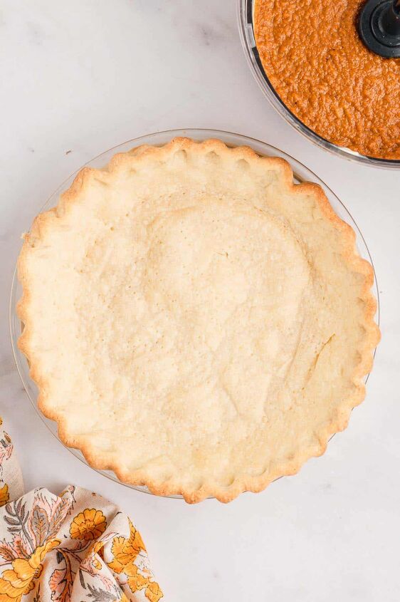 southern sweet potato pie recipe, A baked Sour Cream pie crust with sweet potato pie filling in a food processor on the side on a white counter