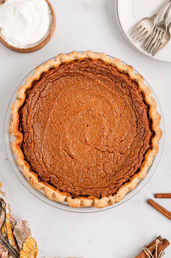 southern sweet potato pie recipe, A full undecorated sweet potato pie with a bowl of whipped cream on the side