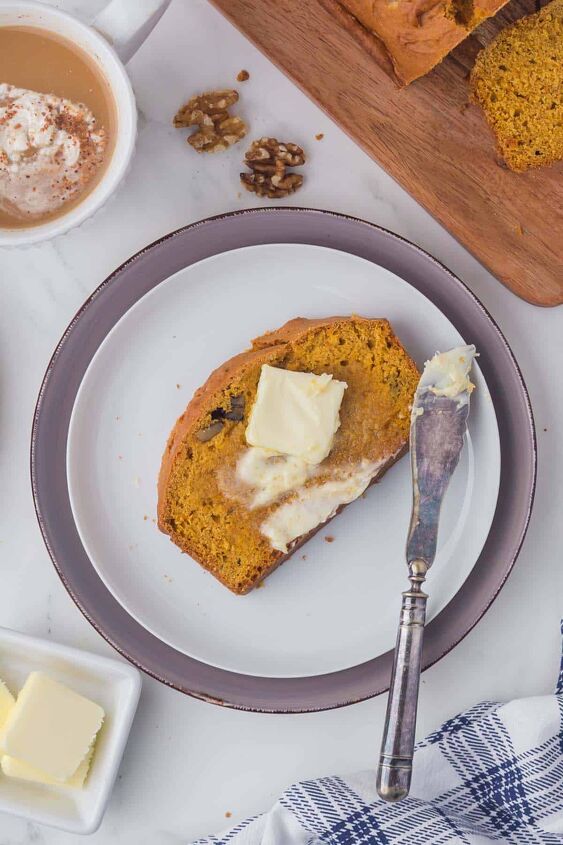 moist pumpkin bread, A piece of pumpkin bread on a white plate with a pat of butter spread on the top with a knife on the side