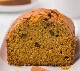 moist pumpkin bread, A loaf of moist Pumpkin bread that has been sliced to see the crumb and walnuts in the bread with a walnut and cinnamon stick in front of it on a white platter