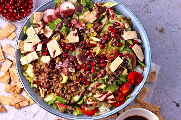 lentil pomegranate salad with tahini dressing, A salad of cooked lentils pomegranate tomatoes pita chips red onions lettuce and dressing