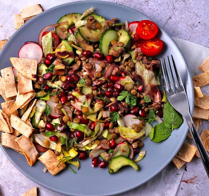 lentil pomegranate salad with tahini dressing, Lentil salad with pomegranate seeds and pita chips on a blue plate