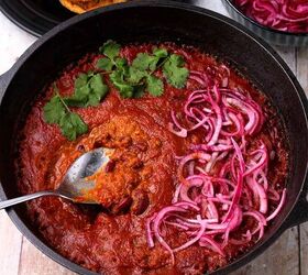 creamy rajma masala vegan kidney bean curry, A black cast iron pot is filled with rajma masala topped with pickled red onions and chopped cilantro