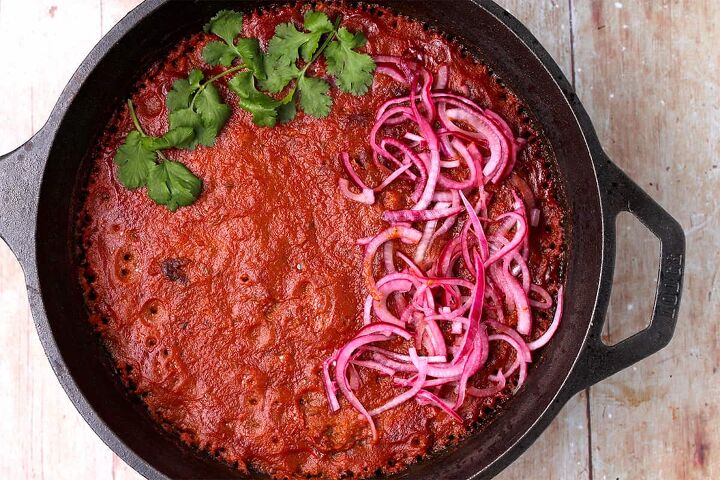 creamy rajma masala vegan kidney bean curry, Baked kidney bean curry in a cast iron pot with sliced red onions and cilantro on top