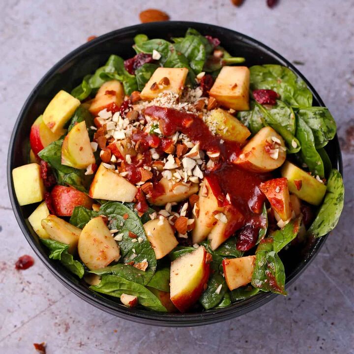 festive pomegranate pearl couscous salad, A bowl of apple cranberry salad with spinach almonds and cranberry balsamic dressing