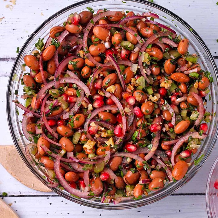 festive pomegranate pearl couscous salad, A bowl of Borlotti bean salad with red onions celery walnuts and pomegranate arils