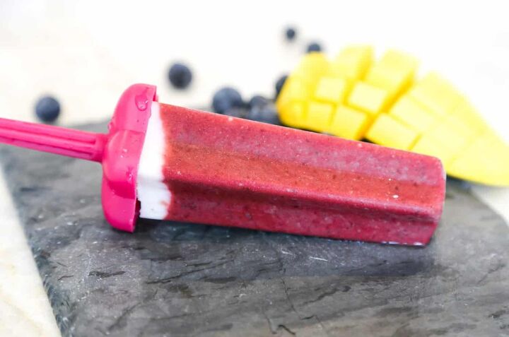 homemade cherry popsicles recipe gluten free vegan, one cherry popsicle with mangos and blueberries in the background