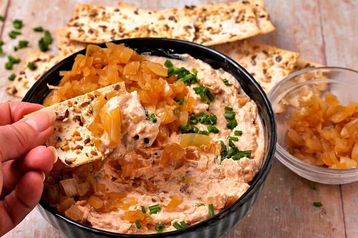 creamy vegan caramelized onion dip no added oil, A cracker is dipped into a bowl of vegan French onion dip with oil free caramelized onions and chives