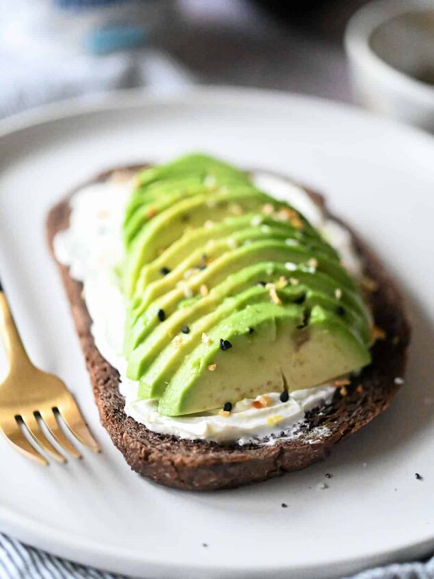 cream cheese avocado toast, Sliced avocado on pumpernickel bread with cream cheese and spices