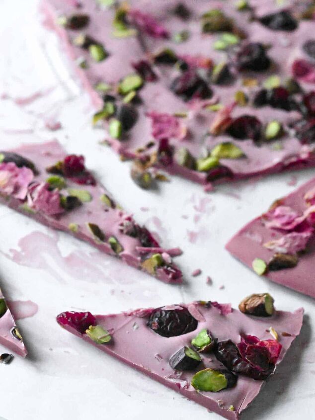 ruby chocolate bark pink chocolate bark, Cut up pieces of pink chocolate bark with pistachios and cranberries on white parchment paper