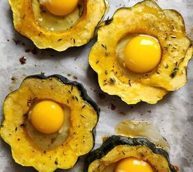 acorn squash egg in a hole with hot honey and thyme, Four acorn squash rings with an uncooked egg in each hole on a baking sheet