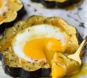 acorn squash egg in a hole with hot honey and thyme, Angled view of acorn squash egg in a hole with a fork bit taken out and dripping yolk