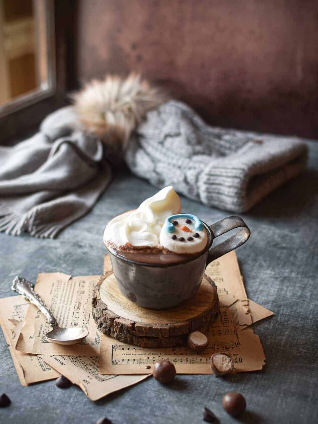 decadent malted milk hot chocolate, Hot chocolate scene by a window with a hat and scarf in the background and scattered malted milk balls