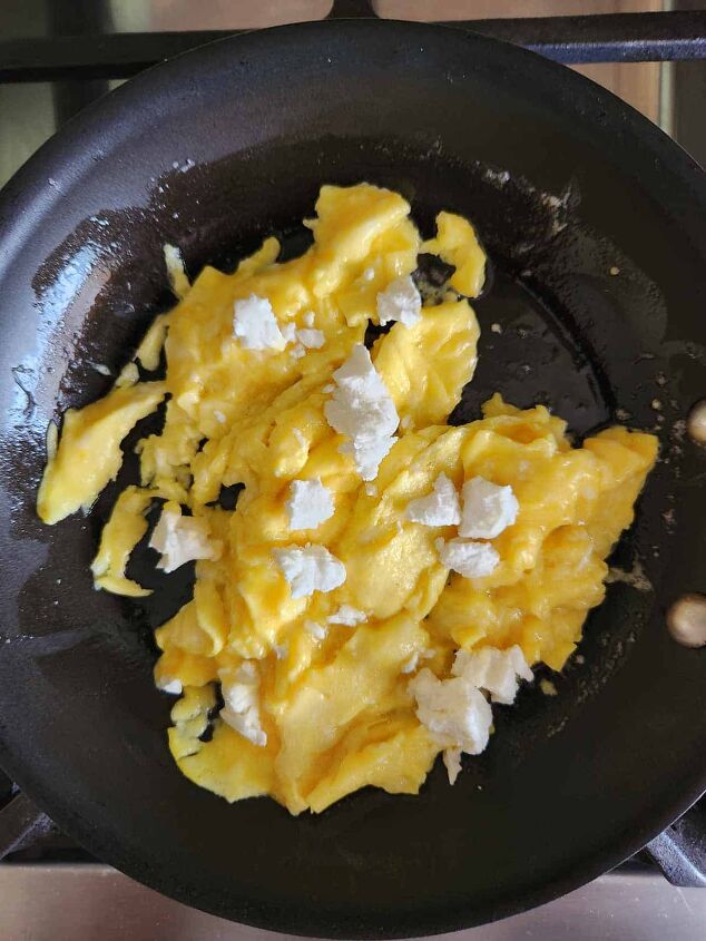 goat cheese scrambled eggs, Scrambled eggs with goat cheese on top in a skillet