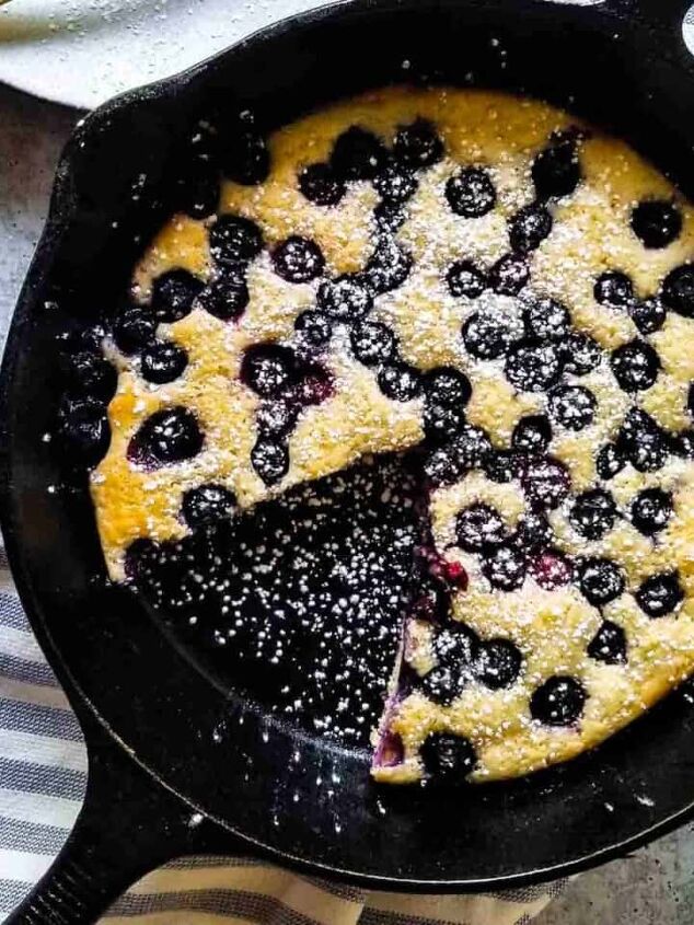 goat cheese scrambled eggs, Overhead view of blueberry pancake skillet with a slice cut out on a plate in a black skillet