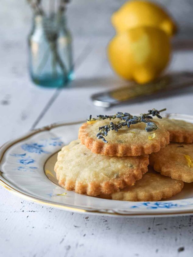 lemon lavender shortbread cookies, Lemon lavender shortbread cookies stacked on top of a floral plate on a wood background