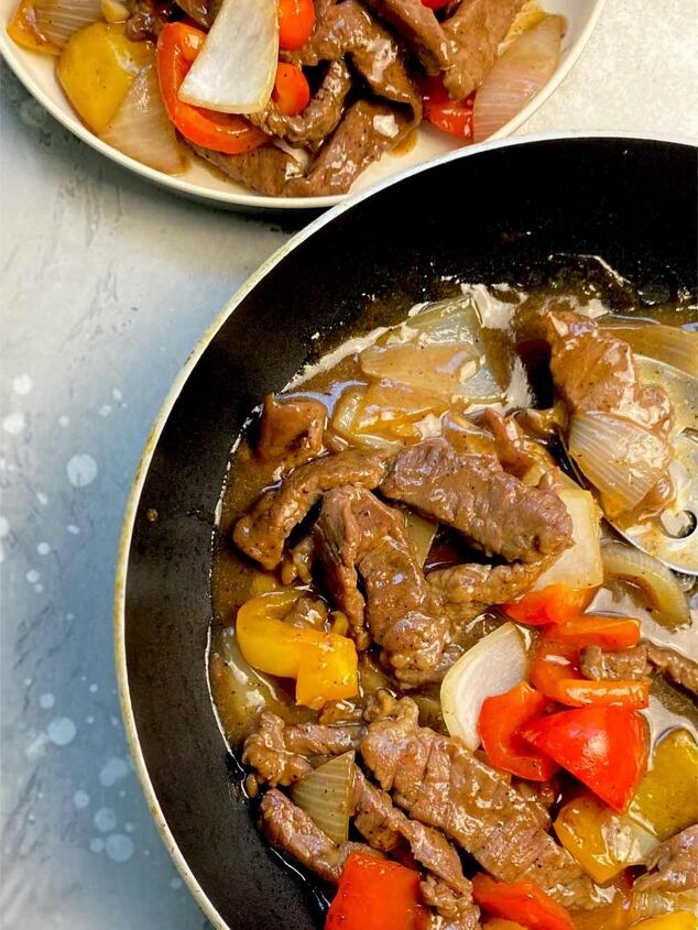 black pepper beef, beef in a pan with a plate on the side
