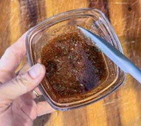 sweet savory air fried butternut squash cubes recipe, glass bowl with spices and oil being stirred with gray spatula
