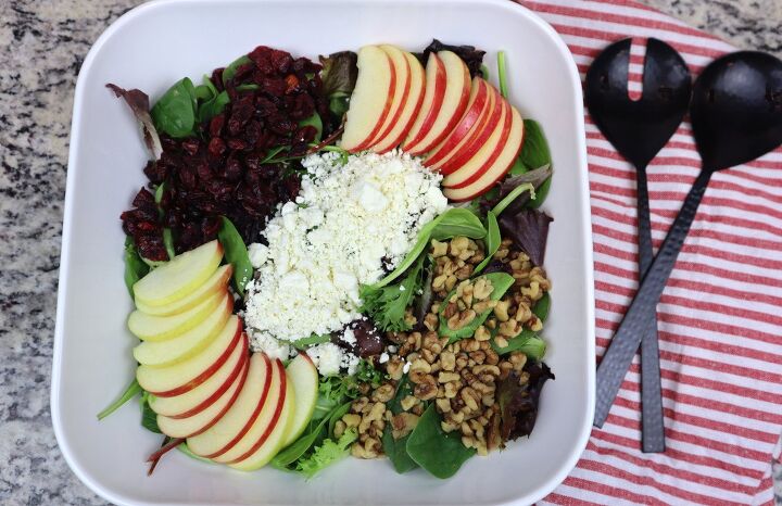 apple spinach salad with cranberries and feta, apple cranberry feta spinach salad in a large white bowl with black salad utensils