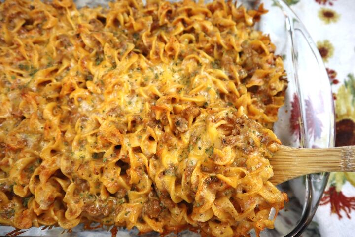 easy cheesy beef noodle casserole recipe, beef noodle casserole in glass dish served with bamboo spoon