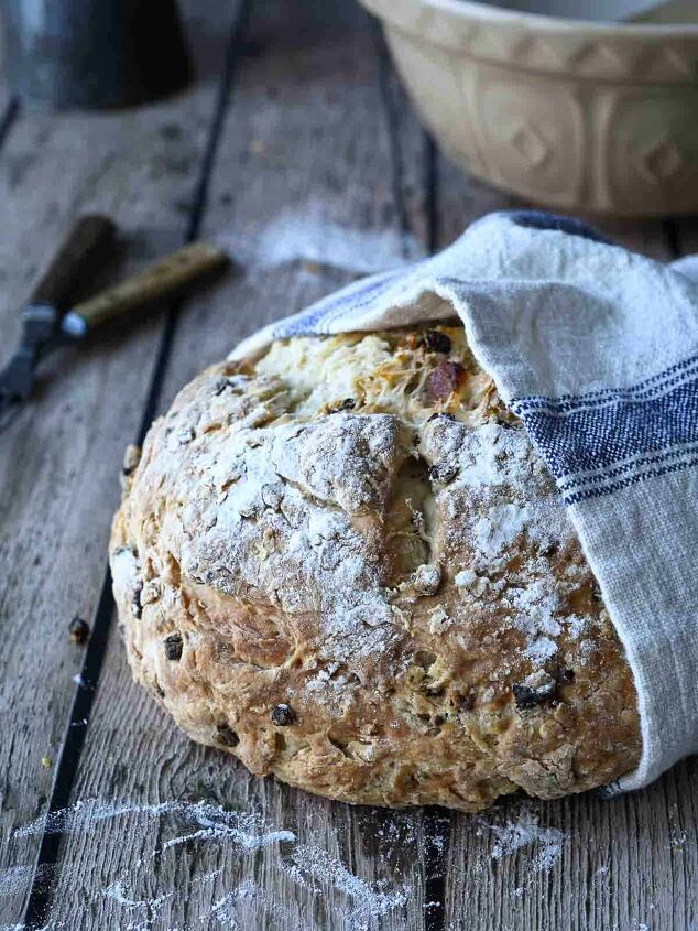 irish soda bread with currants and apricots, Irish soda bread loaf wrapped in a beige and blue towel on a wood surface