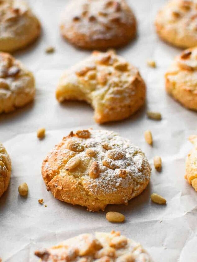 irish soda bread with currants and apricots, Angled view of baked Italian pignoli cookies on a baking sheet covered with white parchment paper One cookie has a bite taken out