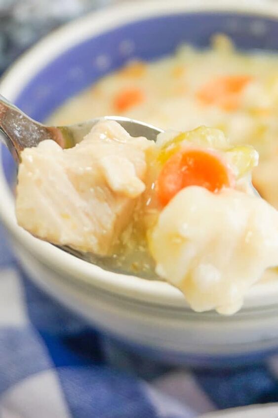 slow cooker chicken and dumplings, a spoonful of Slow Cooker Chicken and Dumplings above more in a white and blue bowl next to a white and blue checkered cloth