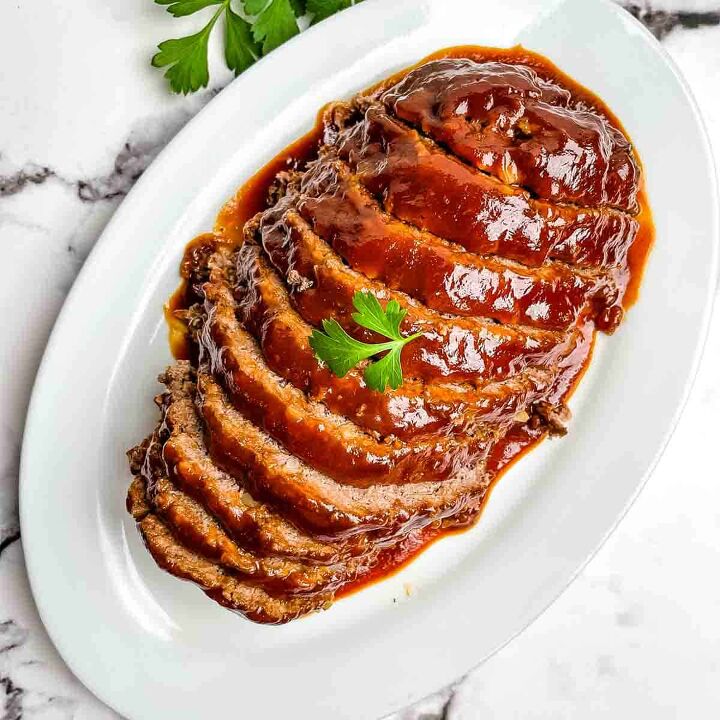 meatloaf recipe with bbq sauce and brown sugar, Homemade meatloaf covered in sauce sliced into servings on a white plate