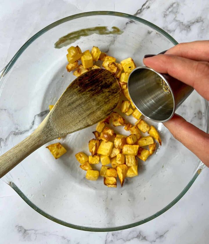 roasted swede oven and air fryer, honey being poured into a bowl of cubed swede There is a wooden spoon in the bowl