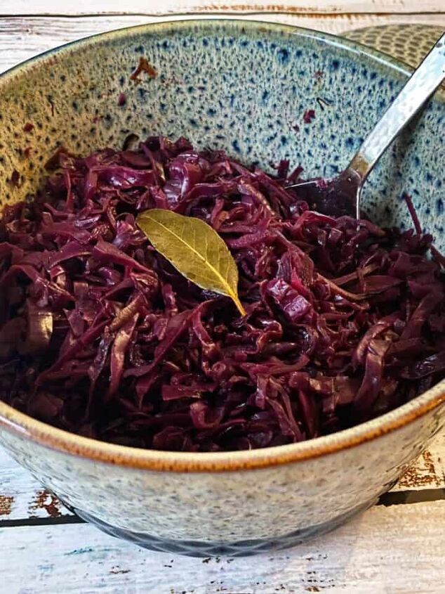 slow cooked leg of lamb in red wine, A casserole dish filled with cooked red cabbage garnished with a bay leaf