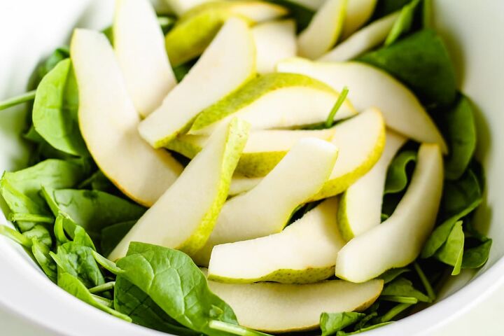 spinach cranberry salad recipe, Pears added on top of green leaves in a bowl