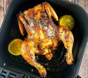 air fryer whole roast chicken with lemon and garlic, Golden brown whole chicken with crispy skin in an air fryer basket garnished with lemon wedges and fresh herbs