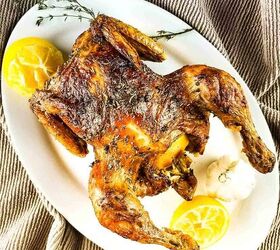 air fryer whole roast chicken with lemon and garlic, The roast chicken on a serving platter with lemon wedges and fresh thyme